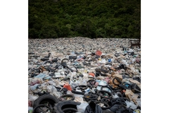 A large pile of garbage in a field, showcasing environmental pollution.
